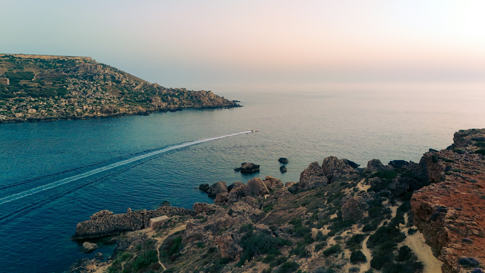 Aerial view of a calm Mediterranean bay at sunset, warm evening light over the water — Mallorca